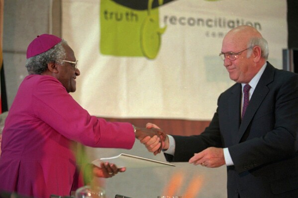 National Party leader F.W. de Klerk, right, hands over the National Party's 30-page submission to the Truth and Reconciliation Commission to the chairman Archbishop Desmond Tutu in Cape Town, Aug. 21 1996. (AP Photo/Sasa Kralj, File)