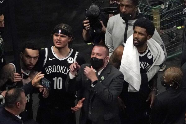 A security guard points as Brooklyn Nets' Kyrie Irving, right with towel, and teammates look up at a fan who reportedly threw a water bottle at him as he left the court after Game 4 during an NBA basketball first-round playoff series, Sunday, May 30, 2021, in Boston. (AP Photo/Elise Amendola)