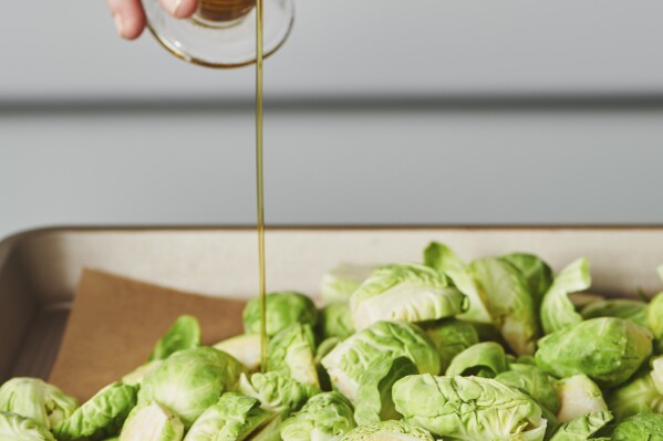 This image provided by Cheyenne Cohen shows olive oil being poured onto Brussel sprouts. Brussels sprouts are often cooked as a side dish, especially during the cold weather months. They are particularly popular as part of holiday meals such as Thanksgiving and Christmas. And if you think you don't like Brussels sprouts, I'm here to say AP food writer Katie Workman says you just haven't had them prepared well. (Cheyenne Cohen via AP)