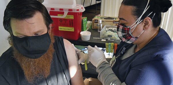 Registered nurse Crystal Monjardin, right, administers the second dose of the Moderna vaccine to Andrew Erwin Tuesday Jan. 19, 2021 at Yuma Regional Medical Center in Yuma, Ariz. The Moderna vaccine, to combat COVID-19, consists of two doses. YRMC personnel received the first dose during Phase 1A of the vaccination allocation plan in late December. (Randy Hoeft/The Yuma Sun via AP)