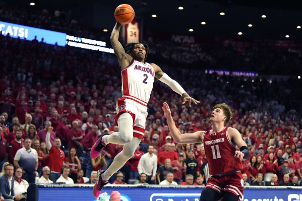 Arizona guard Caleb Love (2) dunks over Wisconsin guard Max Klesmit (11) during the first half of an NCAA college basketball game, Saturday, Dec. 9, 2023, in Tucson, Ariz. (AP Photo/Rick Scuteri)