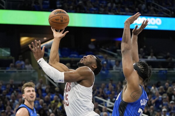 Cleveland Cavaliers guard Donovan Mitchell, center, shoots as he gets past Orlando Magic center Wendell Carter Jr., right, during the first half of Game 6 of an NBA basketball first-round playoff series, Friday, May 3, 2024, in Orlando, Fla. (AP Photo/John Raoux)