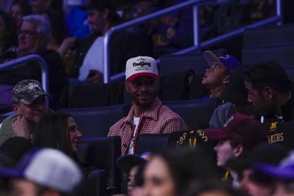 Los Angeles Dodgers player Mookie Betts, center, looks on during the first half of an NBA basketball game between the Los Angeles Lakers and the New York Knicks, Monday, Dec. 18, 2023, in Los Angeles. (AP Photo/Ryan Sun)