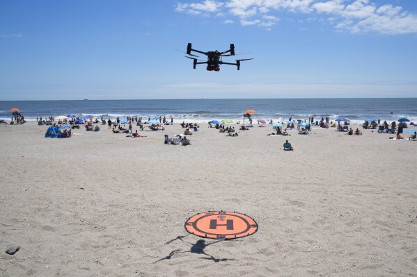 A drone lands for a battery swap at Rockaway Beach in New York, Thursday, July 11, 2024. A fleet of drones patrolling New York City’s beaches for signs of sharks and struggling swimmers is drawing backlash from an aggressive group of seaside residents: local shorebirds. Since the drones began flying in May, flocks of birds have repeatedly swarmed the devices, forcing the police department and other city agencies to adjust their flight plans. (AP Photo/Seth Wenig)