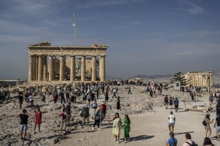 FILE - Tourists visit the Acropolis hill with the 2,500-year-old Parthenon temple on the left, and the ancient Erechtheion temple on the right, in Athens, Greece, on Oct. 11, 2022. Culture Minister Lina Mendoni said Wednesday, Aug. 2, 2023, that visits to the Acropolis of Athens, Greece's most popular archaeological site, will be capped from next month at a maximum 20,000 daily with varying hourly entry limits. (AP Photo/Petros Giannakouris, File)