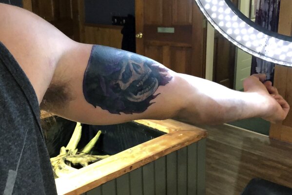 In this Friday, June 19, 2020, photo, Dylan Graves of Ludlow, Vt., shows a completed tattoo after artist Alexander Lawrence in Bellows Falls, Vt., covered up a previous tattoo that contained the image of a swastika on his arm. Lawrence said he has always covered up or removed offensive tattoos for free, but the demand has increased since the death of George Floyd and the resurgence of the Black Lives Matter movement. (AP Photo/Wilson Ring)