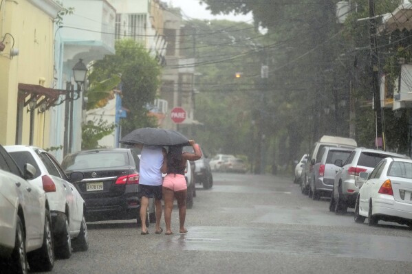 People walk in the rain brought by Tropical Storm Franklin in Santo Domingo, Dominican Republic, early Wednesday, Aug. 23, 2023. (AP Photo/Ricardo Hernandez)