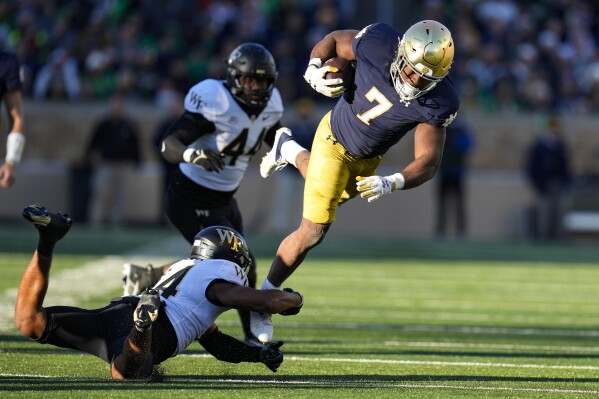 Wake Forest defensive back Evan Slocum (14) trips up Notre Dame running back Audric Estime (7) during the first half of an NCAA college football game in South Bend, Ind., Saturday, Nov. 18, 2023. (AP Photo/Michael Conroy)