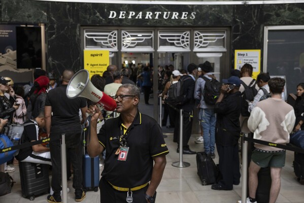 An employee instructs customers at a departure area for Spirit Airlines at LaGuardia Airport in New York on Friday, July 19, 2024. (AP Photo/Yuki Iwamura)