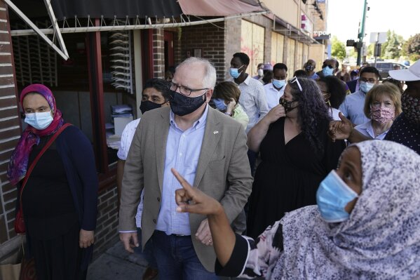 Minnesota Gov. Tim Walz walks with business owners that were affected by events following the George Floyd protests Friday, June 5, 2020 at Hawthorne Crossings in north Minneapolis. Floyd died after being restrained by Minneapolis police officers on May 25. (Anthony Souffle/Star Tribune via AP)