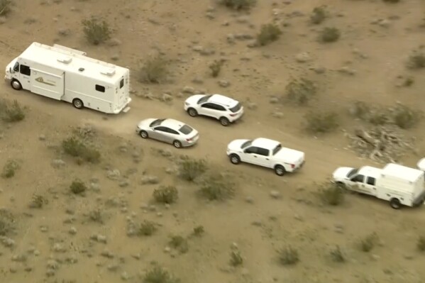 FILE - This aerial still image from video provided by KTLA shows law enforcement vehicles where several people were found shot to death in El Mirage, Calif., Wednesday, Jan. 24, 2024. Prosecutors filed murder charges Tuesday, Jan. 30, 2024, against five suspects in the fatal shootings of six men at a remote dirt crossroads in the Southern California desert after what investigators said was a dispute over marijuana. (KTLA via AP, File)