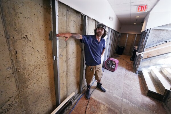 Wyatt Galfetti, who works for Union Mutual Fire Insurance, shows the flooding waterline of his basement office following July floods, Tuesday, Aug. 1, 2023, in Montpelier, Vt. The mostly gutted shops, restaurants and businesses that lend downtown Montpelier its charm are considering where and how to rebuild in an era when extreme weather is occurring more often. Vermont's flooding was just one of several major flood events around the globe this summer that scientists have said are becoming more likely due to climate change. (AP Photo/Charles Krupa)