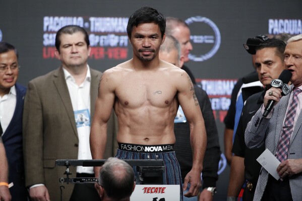 FILE - Manny Pacquiao stands on the scale during a weigh-in Friday, July 19, 2019, in Las Vegas. Pacquiao is scheduled to fight Keith Thurman in a welterweight championship boxing match Saturday in Las Vegas. The International Olympic Committee will not change its rules to let boxing great Manny Pacquiao compete at the Paris Games aged five years beyond the entry limit. Pacquiao wanted to come out of retirement to box at age 45 in the Olympic tournament in Paris where medal bouts will be staged at the Roland Garros tennis complex. (AP Photo/John Locher, File)