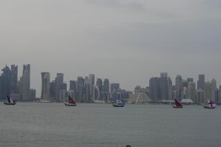 Boats with flags of quarterfinal participating countries pass the skyline of Doha, Qatar, on Wednesday, Dec. 7, 2022. (AP Photo/Frank Augstein)