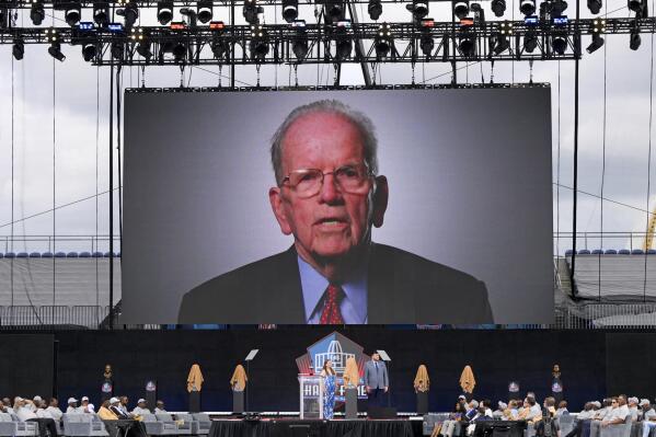 FILE - A video of NFL official Art McNally is played during an induction ceremony at the Pro Football Hall of Fame in Canton, Ohio, Saturday, Aug. 6, 2022. Art McNally, the first on-field official inducted into the Pro Football Hall of Fame, has died. He was 97. His son, Tom McNally, said Monday, Jan. 2, 2023, that his father died of natural causes at a hospital in Newtown, Pennsylvania, near his longtime home. (AP Photo/David Dermer, File)