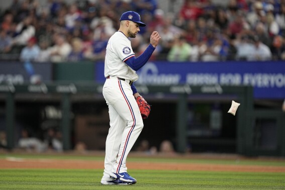 Texas Rangers' Nathan Eovaldi tosses the rosin bag as he walks behind the mound before throwing to Washington Nationals' Luis Garcia Jr. in the sixth inning of a baseball game in Arlington, Texas, Thursday, May 2, 2024. Eovaldi left the game with an unknown injury in the inning. (AP Photo/Tony Gutierrez)