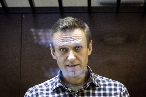 FILE - Russian opposition leader Alexei Navalny looks at photographers from inside a glass cage in the Babuskinsky District Court in Moscow, Russia, on Feb. 20, 2021. Imprisoned opposition leader Alexei Navalny has been handed new charges by Russian prosecutors. The 47-year-old is already serving more than 30 years in prison after being found guilty of crimes including extremism — charges that his supporters characterize as politically motivated. In comments passed to his associates, Navalny said he had been charged under article 214 of Russia’s penal code, which covers crimes of vandalism (AP Photo/Alexander Zemlianichenko, File)