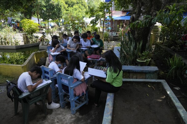 Students hold class under trees because the school was converted into a temporary evacuation center at Malilipot town, Albay province, northeastern Philippines, Thursday, June 15, 2023. Thousands of residents have left the mostly poor farming communities within a 6-kilometer (3.7-mile) radius of Mayon's crater in forced evacuations since volcanic activity spiked last week. (AP Photo/Aaron Favila)