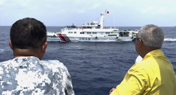 In this image made from video provided by PTV4 (People's Television News) Government Channel, Philippine special envoy to China Teodoro Locsin Jr., right, looks at a Chinese Coast Guard ship near the Second Thomas Shoal on Oct. 4, 2023, while onboard a Philippine coast guard vessel that escorted two Philippine boats to deliver food and other supplies to a Filipino marine territorial outpost in the Second Thomas Shoal. (Patrick de Jesus/PTV4 via AP)