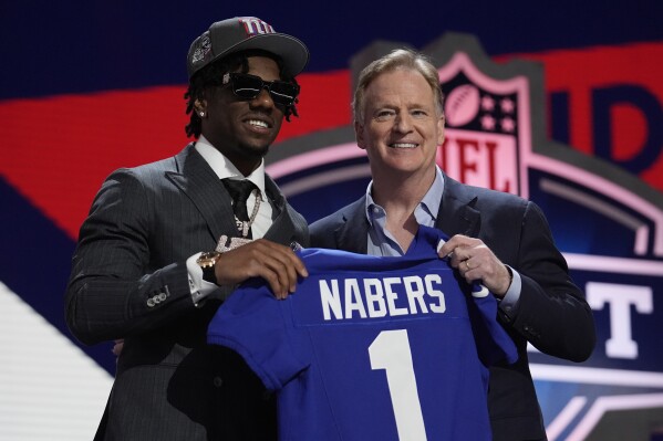 LSU wide receiver Malik Nabers, left, poses with NFL Commissioner Roger Goodell after being chosen by the New York Giants with the sixth overall pick during the first round of the NFL football draft, Thursday, April 25, 2024, in Detroit. (AP Photo/Jeff Roberson)