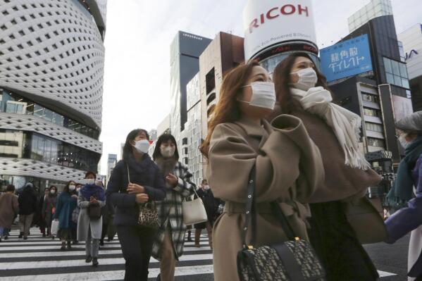 People wearing face masks to protect against the spread of the coronavirus walk on a street in Tokyo Tuesday, Jan. 25, 2022. (AP Photo/Koji Sasahara)
