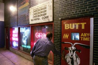 FILE - In this Sept. 23, 2005 file photo, a customer enters the Billy Goat Tavern under Chicago's Michigan Ave.  The once-busy diner tucked below a Michigan Avenue overpass in Chicago famously inspired a Saturday Night Live skit starring John Belushi and Bill Murray as short-order cooks. But the money the Billy Goat Tavern is losing now due to state-imposed business closures during the coronavirus outbreak is no joke. (AP Photo/Charles Rex Arbogast, File)