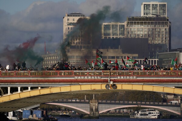 Protesters wave flags and hold flares during a pro-Palestinian protest in London, Saturday, Nov. 11, 2023. London police have stepped up efforts to ensure a pro-Palestinian march on Saturday remains peaceful following a week of political sparring over whether the demonstration should go ahead on the weekend Britain honors its war dead.(AP Photo/Alberto Pezzali)