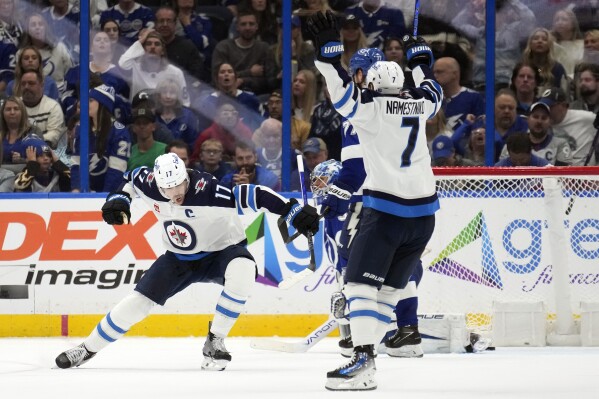 Winnipeg Jets center Adam Lowry (17) celebrates with center Vladislav Namestnikov (7) after scoring the game-winning goal past Tampa Bay Lightning goaltender Jonas Johansson during overtime an NHL hockey game Wednesday, Nov. 22, 2023, in Tampa, Fla. (AP Photo/Chris O'Meara)