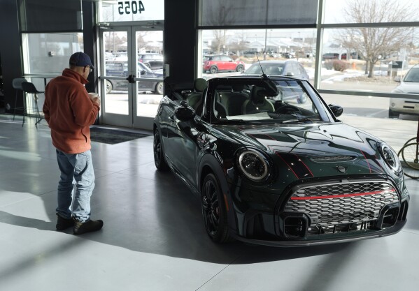 FILE - A man looks at a 2024 Cooper S John Cooper Works convertible at a Mini dealership on Nov. 30, 2023, in Loveland, Colo. Automobile prices, which had been fueling inflation in the U.S., are starting to drop, helping to slow overall consumer price increases and giving buyers hope of getting a deal. (AP Photo/David Zalubowski, File)