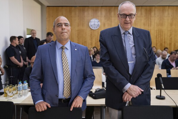 Deputy federal spokesperson for Alternative for Germany party (AfD) Peter Boehringer, left, and assessor on the AfD's federal executive board Roman Reusch stand in the courtroom before the verdict in the appeal proceedings in the dispute over the classification of the AfD by the Federal Office for the Protection of the Constitution at the Higher Administrative Court for the state of North Rhine-Westphalia, in Muenster, Germany, Monday May 13, 2024. The administrative court in Muenster ruled in favor of the BfW intelligence agency on Monday, upholding a 2022 decision by a lower court in Cologne. Alternative for Germany, or AfD, has rejected the designation strongly. The party could still seek to appeal the verdict at a federal court. (Guido Kirchner/dpa/dpa via AP)