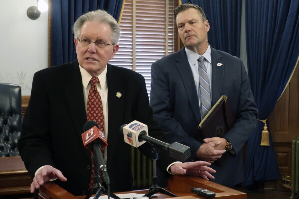 Kansas state Sen. Mike Thompson, R-Shawnee, answers questions from reporters about proposed restrictions on foreign ownership of land in Kansas as Kansas Attorney General Kris Kobach watches, during a news conference Tuesday, Feb. 6, 2024 at the Statehouse in Topeka, Kan. Democratic Gov. Laura Kelly has vetoed proposed restrictions approved by the Republican-controlled Legislature. (AP Photo/John Hanna)