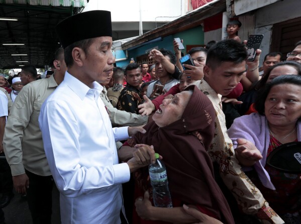 FILE - Indonesian President Joko Widodo, left, listens to an elderly woman during his visit to Tanah Tinggi, a low-income neighborhood in Jakarta, Indonesia, July 26, 2019.  , Indonesia's presidential bid highlighted how far the world's third-largest democracy had moved from its brutal authoritarian era a decade earlier.  With his second and final five-year term ending in October, Widodo, whom some consider Asia's Barack Obama, is leaving behind an ambitious series of impressive economic development and infrastructure projects, including decongesting Indonesia's crowded capital. Also includes a $33 billion plan to relocate.  Marginal island of Borneo.  (AP Photo/Dita Alangkara, File)