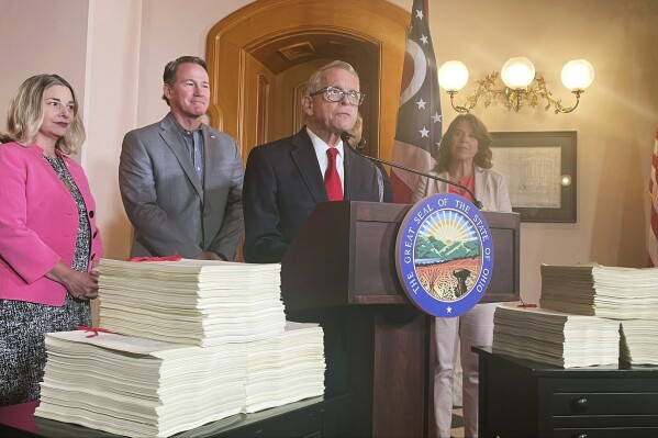 Ohio Gov. Mike DeWine, surrounded by the over 6,000 pages making up Ohio's $86 million state budget, addresses reporters at a press conference, Wednesday, July 5, 2023, at the Ohio Statehouse in Columbus, Ohio. (AP Photo/Samantha Hendrickson)