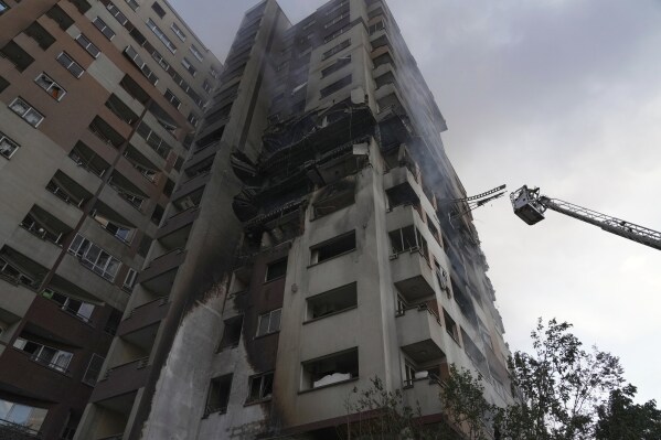 A firefighter stands on a crane at the scene of an explosion at a residence compound after Israeli attacks in Tehran, Friday, June 13, 2025. (AP Photo/Vahid Salemi)