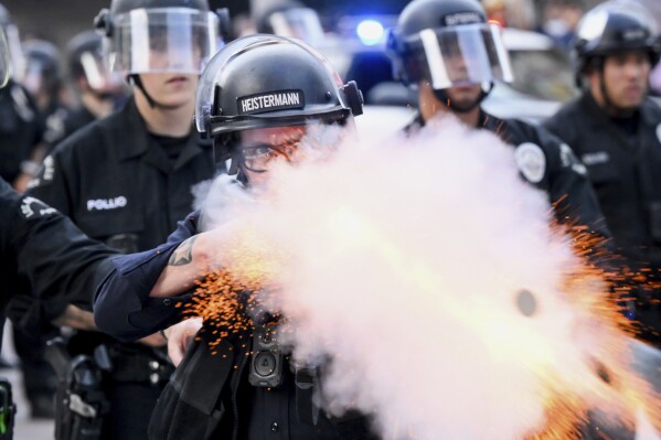 A law enforcement officer fires a less-lethal projectile during a protest Saturday, June 14, 2025, in Los Angeles. (AP Photo/Noah Berger)