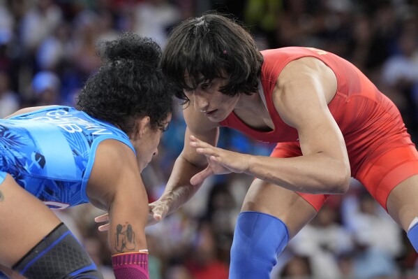 CORRECTS NAME TO VINESH PHOGAT, NOT VINESH VINESH - India's Vinesh Phogat and Cuba's Yusneylys Guzman, right, compete during their women's freestyle 50kg wrestling semifinal match, at Champ-de-Mars Arena, during the 2024 Summer Olympics, Tuesday, Aug. 6, 2024, in Paris, France. (AP Photo/Eugene Hoshiko)