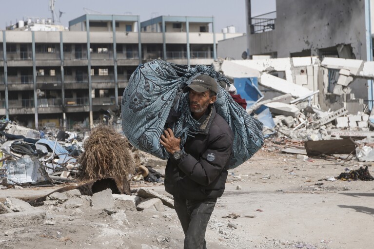 A Palestinian carries his belongings after visiting their houses destroyed in the Israeli offensive on Khan Younis, Gaza Strip, Wednesday, March 6, 2024. (AP Photo/Mohammed Dahman)