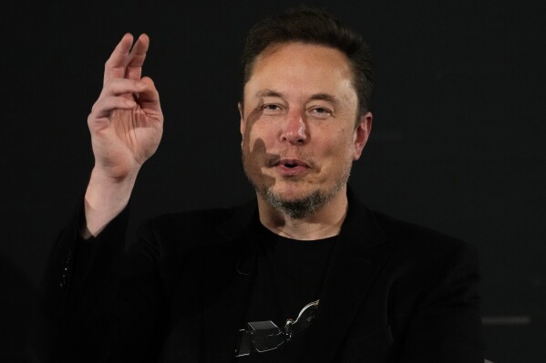 FILE - Elon Musk, owner of social media platform X, gestures during an event with Britain's Prime Minister Rishi Sunak in London on Nov. 2, 2023. The world could have its first trillionaire within a decade, anti-poverty organization Oxfam International said Monday Jan. 15, 2024 in its annual assessment of global inequalities timed to the gathering of political and business elites at the Swiss ski resort of Davos. (AP Photo/Kirsty Wigglesworth, Pool, File)