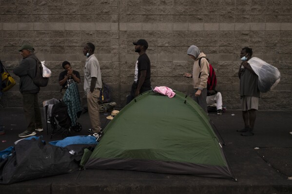 Homeless people wait in line for dinner outside the Midnight Mission in the Skid Row area of Los Angeles, Wednesday, Oct. 25, 2023.  (AP Photo/Jae C. Hong)