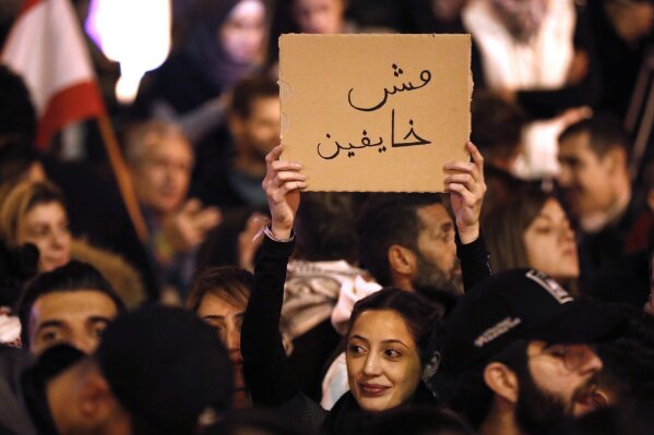 Anti-government protesters holds an Arabic placard that reads:"We are not fearing," during a protest near the parliament square, in downtown Beirut, Lebanon, Sunday, Dec. 15, 2019. Lebanese security forces fired tear gas, rubber bullets and water cannons Sunday to disperse hundreds of protesters for a second straight day, ending what started as a peaceful rally in defiance of the toughest crackdown on anti-government demonstrations in two months. (AP Photo/Hussein Malla)