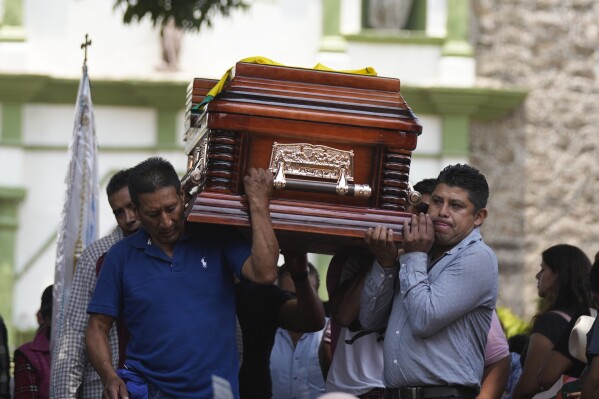 Relatives and friends carry the coffin that contain the remains of man slain in a mass shooting, during a funeral procession in Huitzilac, Mexico, Tuesday, May 14, 2024. The shooting in the mountain township beset by crime just south of Mexico City resulted in several deaths, authorities said Sunday. (AP Photo/Fernando Llano)