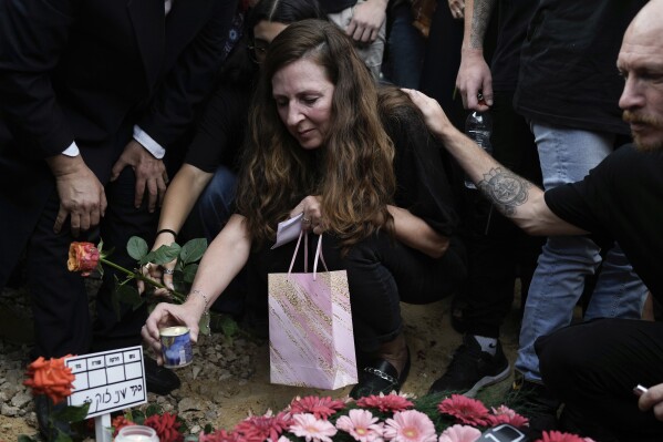 Ricarda Louk places a candle on the grave of her daughter Shani Louk during her funeral in Srigim, Israel, on Sunday, May 19, 2024. Louk, a 22-year-old German-Israeli, was killed while fleeing a music festival during Hamas' Oct. 7 attack and her body was taken into Gaza. Israeli forces recovered her remains last week along with those of three other Israelis killed during the attack, which ignited the war in Gaza. (AP Photo/Leo Correa)