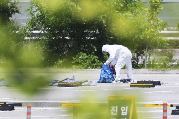 An officer wearing protective gear collects the trash from a balloon presumably sent by North Korea, in Siheung, South Korea, Sunday, June 2, 2024. (Hong Ki-won/Yonhap via AP)