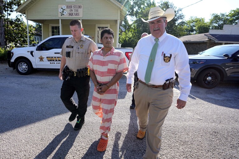 FILE - Francisco Oropeza, center, is escorted to the San Jacinto County courthouse by San Jacinto County Sheriff Greg Capers, right, for a hearing Thursday, May 18, 2023, in Coldspring, Texas. Oropeza is suspected of killing five people, including a young boy, after neighbors asked him to stop firing off rounds in his yard. (AP Photo/David J. Phillip, File)