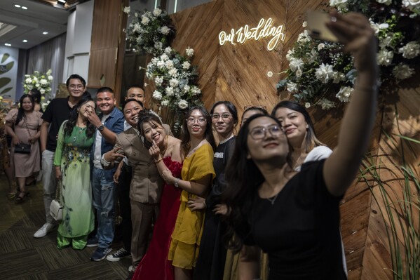 A bride and groom take a group picture with their guests after a wedding ceremony in Ho Chi Minh City, Vietnam, Jan. 14, 2024. (AP Photo/Jae C. Hong)