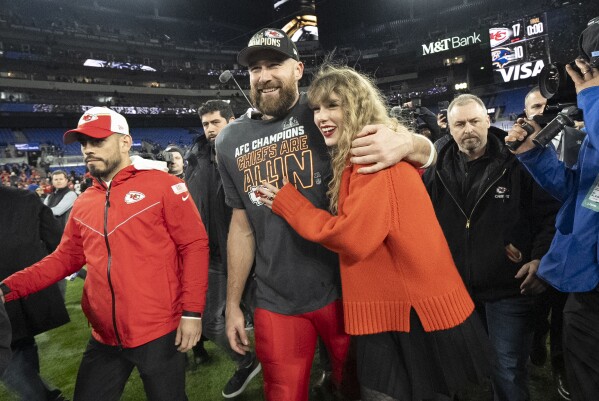 FILE - Kansas City Chiefs tight end Travis Kelce and Taylor Swift walk together after an AFC Championship NFL football game between the Chiefs and the Baltimore Ravens, Jan. 28, 2024, in Baltimore.  For weeks, scrutiny over Swift's travels has been mounting on social media, with people pointing out the planet-warming carbon dioxide emissions released with each flight.  (AP Photo/Julio Cortez, File)