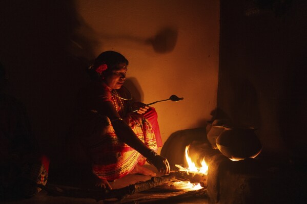 Sunita Muduli, 34, from the Paroja Indigenous community cooks on a clay oven in Putpondi village, Koraput district, in India's eastern state of Odisha, Tuesday, April 15, 2025. (AP Photo/Rafiq Maqbool)