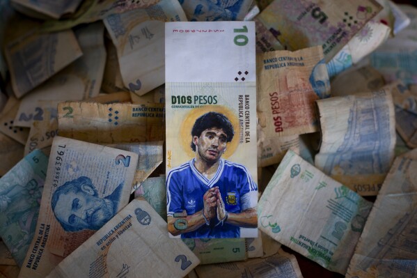 A piece of Money Art by artist Sergio Díaz features the late soccer legend Diego Maradona with his in hands wrapped in a rosary and a halo behind his head, painted on an Argentine ten-peso banknote, in Diaz's studio in Salta, Argentina, Saturday, Sept. 9, 2023. (AP Photo/Javier Corbalan)