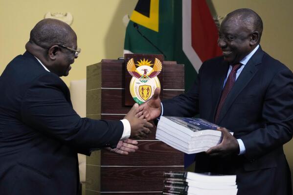 South Africa's President Cyril Ramaphosa, right, receives the final report of a judicial investigation into corruption from Chief Justice Raymond Zondo at Union Building in Pretoria, South Africa, Wednesday, June 22, 2022. The probe has laid bare the rampant corruption in government and state-owned companies during former President Jacob Zuma’s tenure from 2009 to 2018. (AP Photo/Themba Hadebe)