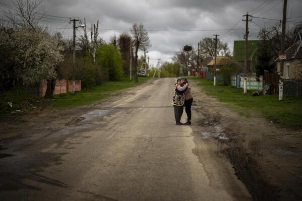 Tetiana Boikiv, 52, right, meets and hugs her neighbor, Svitlana Pryimachenko, 48, during a funeral service for her husband, Mykola "Kolia" Moroz, 47, in the Ukrainian village of Ozera, near Bucha, on Tuesday, April 26, 2022. (AP Photo/Emilio Morenatti)